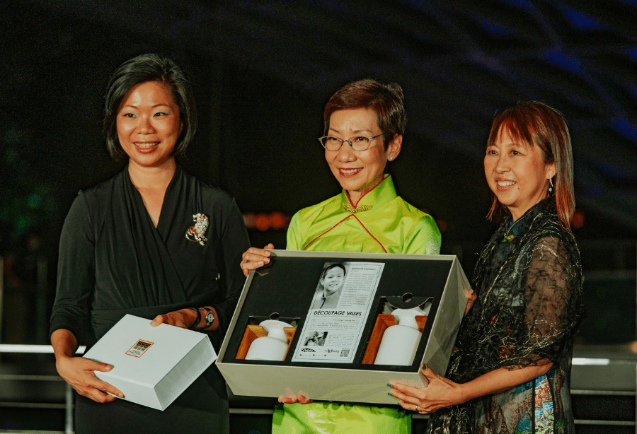 Three women on stage holding a framed award at the DBCS recognition event