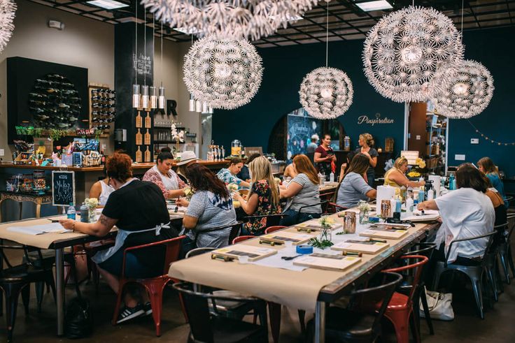 Guests seated at long tables crafting together at a Pinspiration events venue under ornate chandeliers