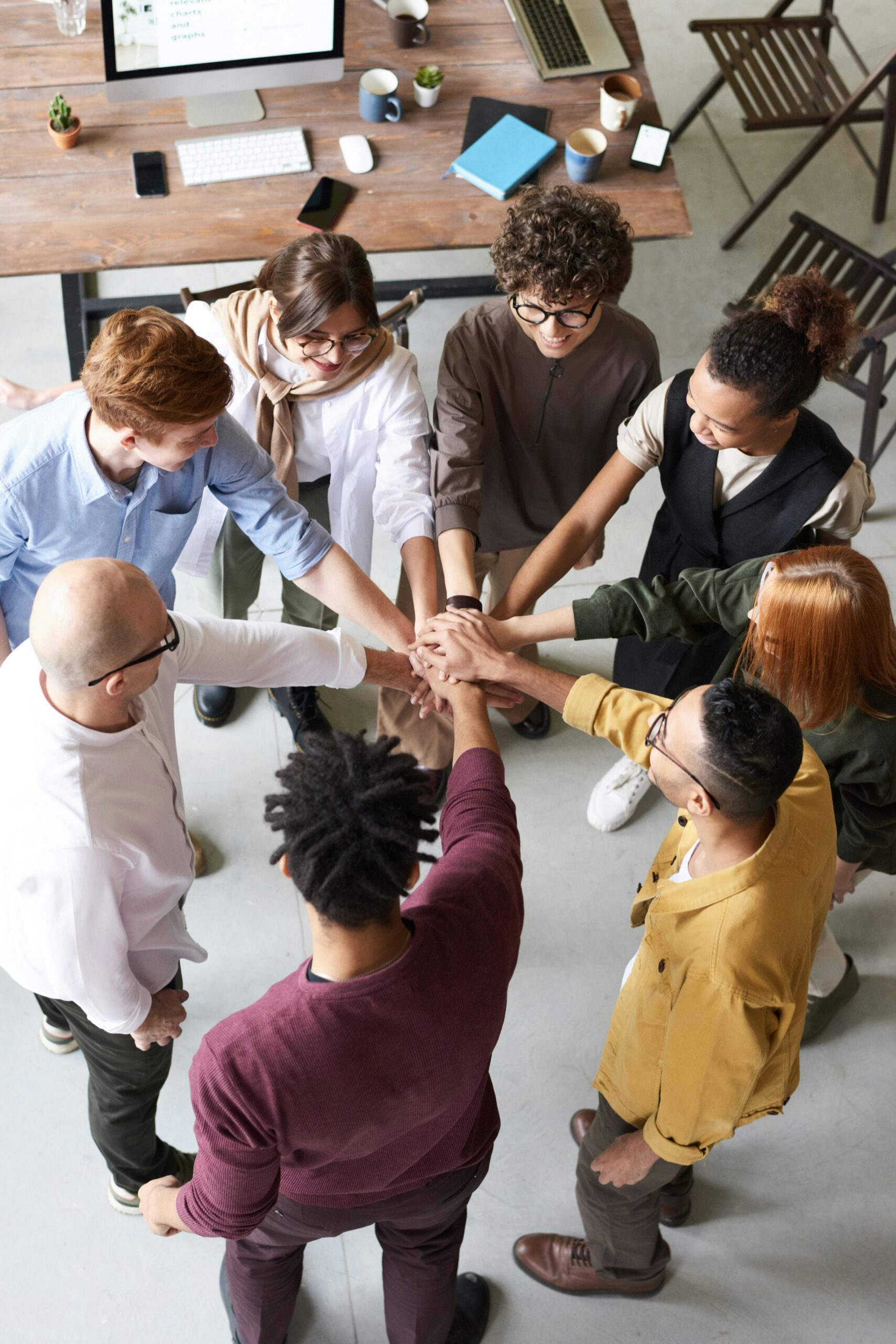 Overhead view of a diverse team stacking hands together in the centre of an office meeting room