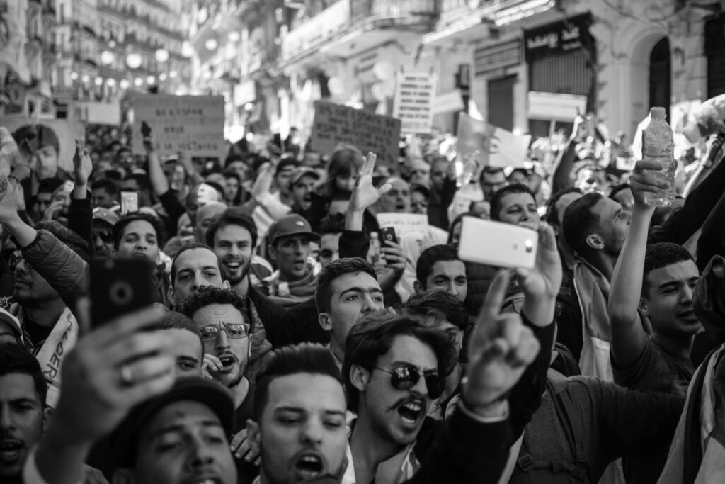 Black and white photo of a passionate crowd chanting and holding signs at a street protest