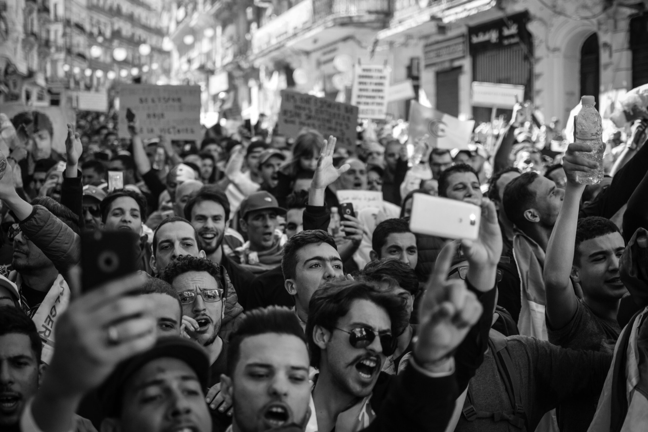 Black and white photo of a passionate crowd chanting and holding signs at a street protest